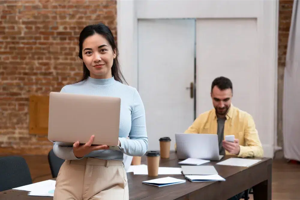 Young corporate woman standing with laptop at work happy with employee benefits young corporate woman standing with laptop at work happy with employee benefits