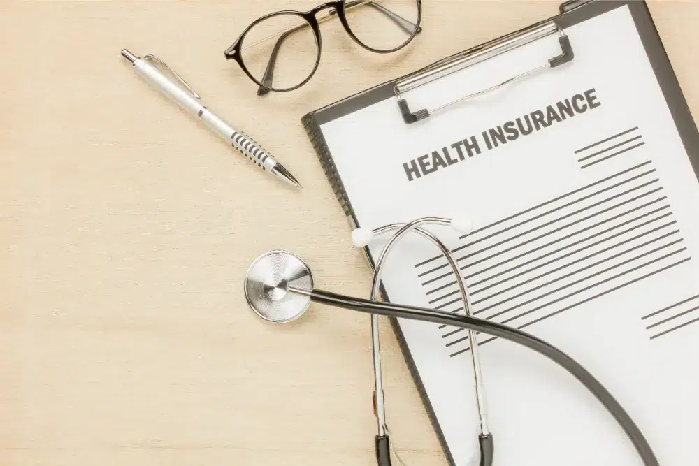 top view health insurance form eyeglasses with stethoscope wooden background business what is group health insurance what is group health insurance