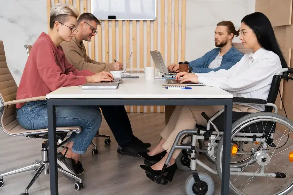 Une équipe travaillant au bureau avec une personne utilisant l’assurance invalidité pour employé une équipe travaillant au bureau avec une personne utilisant l’assurance invalidité pour employé