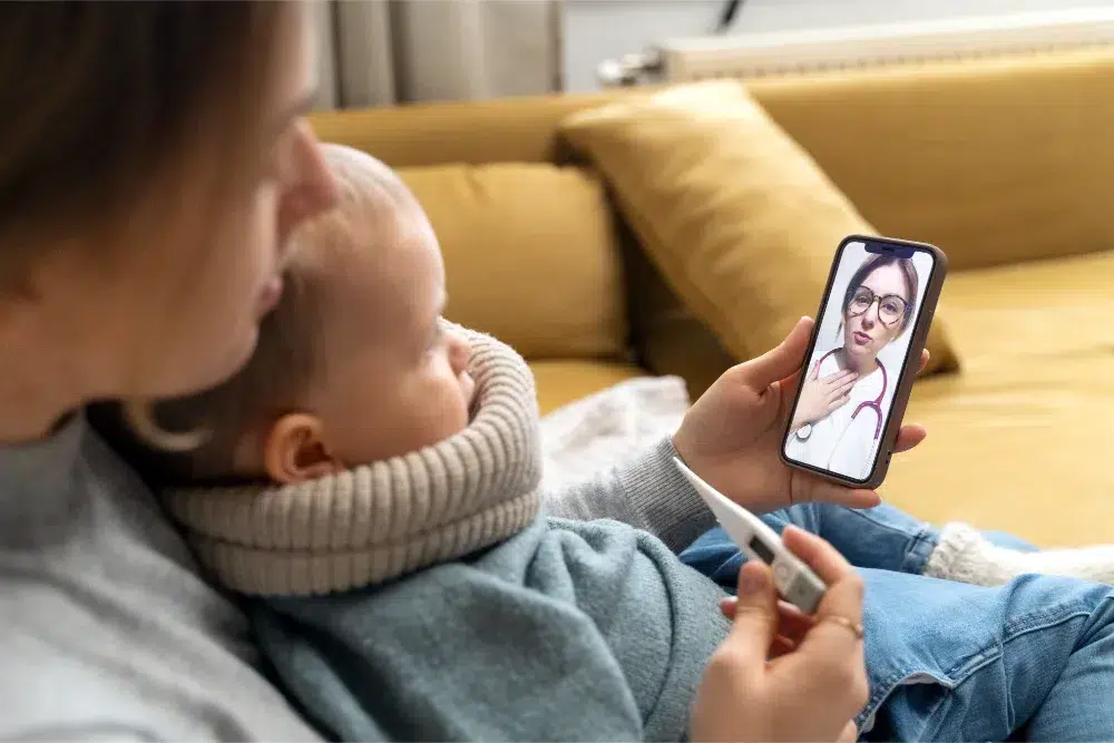 A mon and her child sitting on a couch and using a phone for telemedicine services a mon and her child sitting on a couch and using a phone for telemedicine services