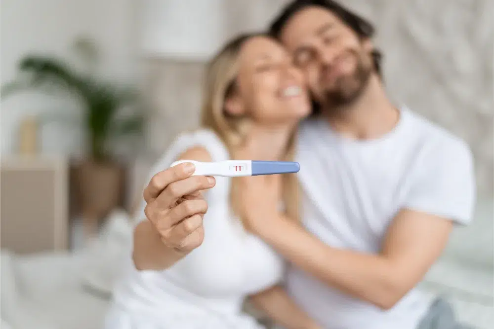 happy caucasian spouses showing positive pregnancy test embracing home selective focus family planning concept fertility spending account