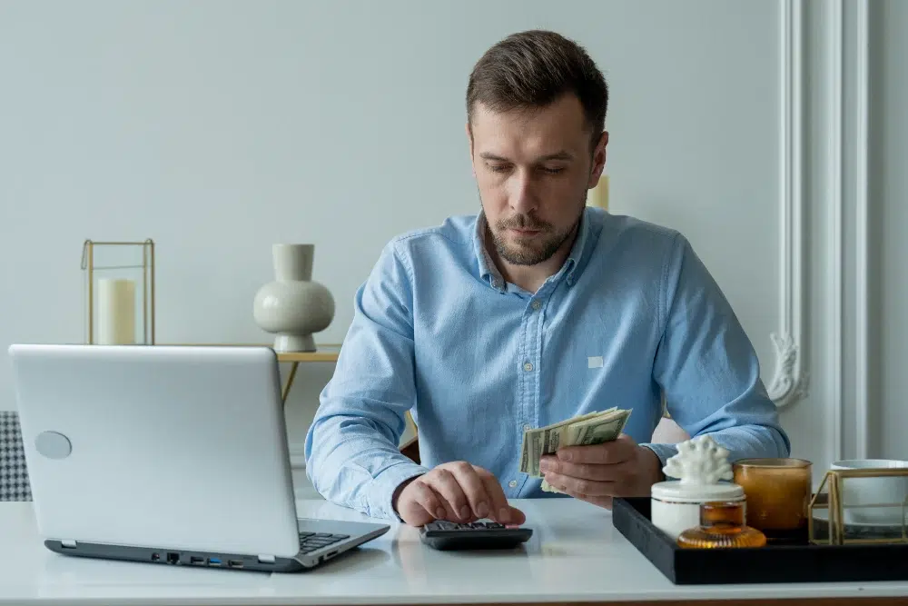 man with money calculator checks bills calculates expenses studies credit balance sitting table home Compte de dépenses pour employés