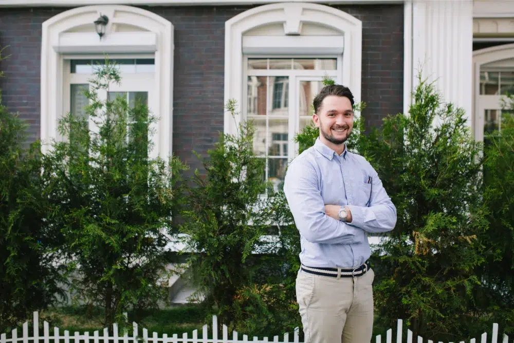 Professional young man standing in front of new home thanks to workplace first home savings account (fhsa) professional young man standing in front of new home thanks to workplace first home savings account (fhsa)