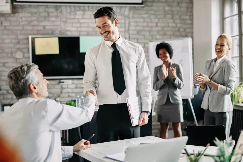 Hommes d’affaires heureux serrant la main de son employeur après avoir reçu unr prime de performance Hommes d’affaires heureux serrant la main de son employeur après avoir reçu unr prime de performance